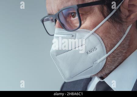 Elegante uomo d'affari che indossa maschera respiratoria protettiva KN95 durante le pandemie di Covid-19, fuoco selettivo Foto Stock