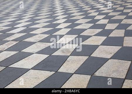 Un pavimento a mosaico costruito con lastre di pietra bianche e nere che coprono Piazza Massena a Nizza, Francia. Foto Stock
