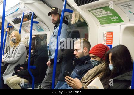 Londra, UK, 28 novembre 2021: Sulla metropolitana di Londra la maggior parte delle persone indossa maschere facciali, che sono obbligatorie a meno che non siano esenti da farmaci, ma spesso ignorate. Dal martedì le maschere facciali diventeranno di nuovo obbligatorie sui trasporti pubblici e nei negozi. Anna Watson/Alamy Live News Foto Stock