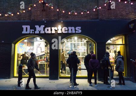 Londra, Regno Unito, 28 novembre 2021: I clienti di Natale tra le luci di Natale nel Covent Garden. Nonostante le preoccupazioni circa la nuova variante del coronavirus e l'imminente imposizione di regole più severe maschera in Inghilterra da martedì, il richiamo di Londra in una domenica pomeriggio soleggiato è stato attraente per gli acquirenti. Le code si sono formate con coloro che sperano di raccogliere un affare dalle offerte del Black Friday ancora in esecuzione. Anna Watson/Alamy Live News Foto Stock