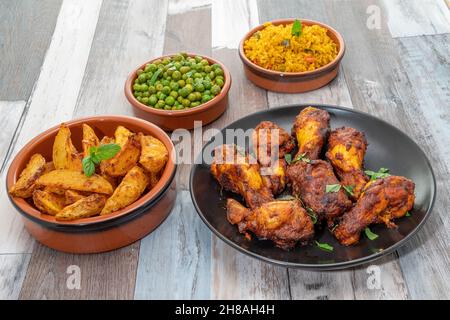 Pasto con ali di pollo peri-Peri con spicchi piccanti, piselli e riso Foto Stock