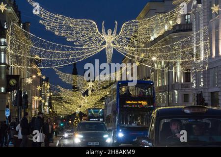 Londra, Regno Unito, 28 novembre 2021: Shopping natalizio tra le luci natalizie di Regent Street e Picadilly Circus nel West End di Londra. Nonostante le preoccupazioni circa la nuova variante del coronavirus e l'imminente imposizione di regole più severe maschera in Inghilterra da martedì, il richiamo di Londra in una domenica pomeriggio soleggiato è stato attraente per gli acquirenti che sperano di raccogliere un affare dalle offerte Black Friday ancora in esecuzione. Anna Watson/Alamy Live News Foto Stock