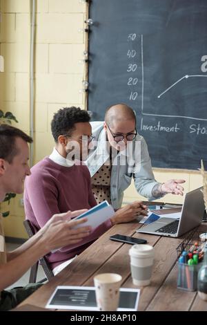 Giovane donna business coach consulenza biraciale uomo d'affari di fronte al laptop tra i colleghi impegnati a seminario o formazione Foto Stock