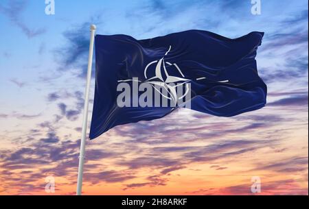 Minsk, Bielorussia - Maggio 2021: Bandiera della NATO che sventola nel vento su flagpole contro il cielo con le nuvole nella giornata di sole. Foto Stock