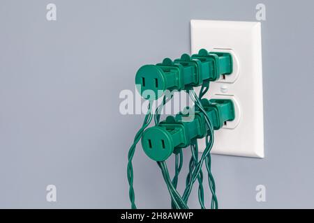 Presa elettrica sovraccarica di luci a corda natalizie. Concetto di sicurezza, pericoli e prevenzione degli incendi per le decorazioni delle festività. Foto Stock