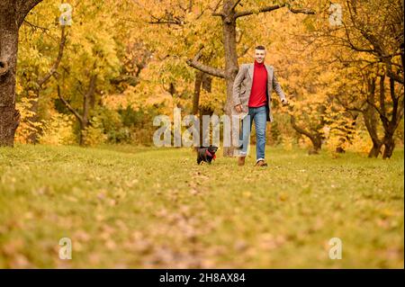 Un uomo che gioca con il suo cane nel parco Foto Stock