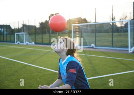 Regno Unito, giocatore di calcio femminile che rimbalza palla in campo al tramonto Foto Stock