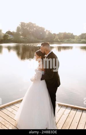 Sposa e sposo abbracciando su lakeshore Foto Stock