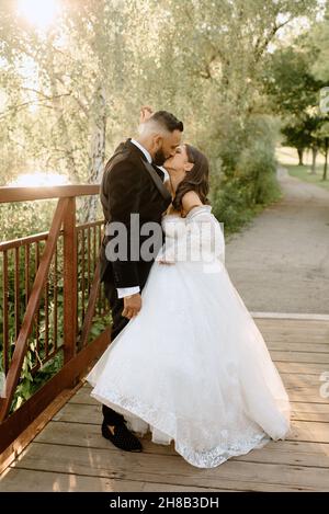 Brilla e lo sposo baciare sulla passerella nel parco Foto Stock