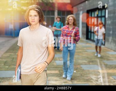 Teen boy cammina lungo la strada estiva dopo aver terminato le lezioni universitarie