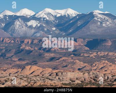 Montagne la SAL innevate con formazioni rocciose nella valle in primo piano. Fotografato ad Arches National Park, Utah. Foto Stock