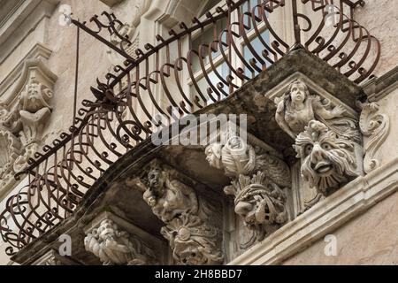 Bel mascaron barocco ornamento di un balcone nel centro storico di Ragusa, Sicilia Foto Stock