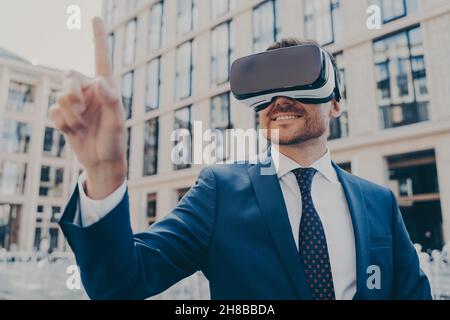 Uomo d'affari in abito blu formale utilizzando occhiali VR all'esterno Foto Stock