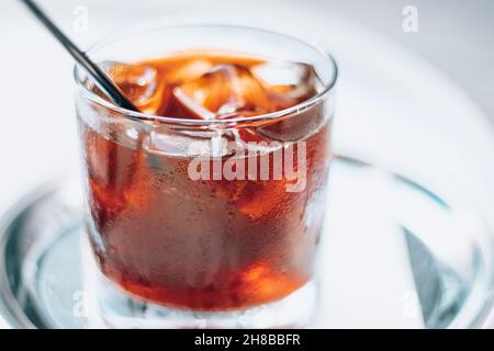 Estrazione a freddo con ghiaccio e paglia nera su sfondo bianco. Deliziosa bevanda fredda con caffè. Foto Stock