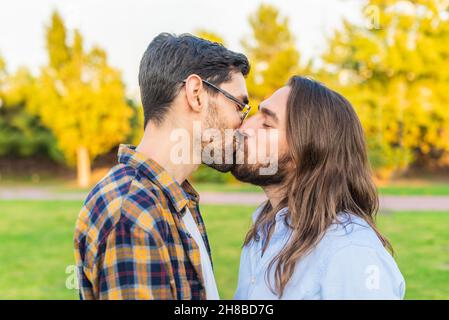 Una giovane coppia gay maschio bacia nel parco. Foto Stock