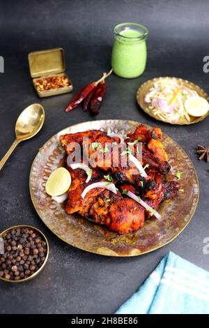 Il pollo Tandoori è una ricetta popolare di pollo arrosto dall'India. Tandoor è un tradizionale forno a legna. Il piatto di Tandoori di pollo viene servito in un piatto nero Foto Stock