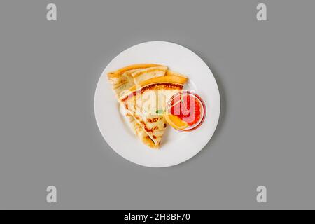 Persona che mangia crepe con caviale rosso. Gustosa colazione su sfondo grigio, vista dall'alto. Foto Stock