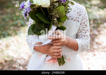 Mani di bambina che regge il bouquet con nastro di seta bianco Foto Stock