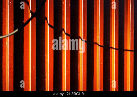 doghe di legno su case dipinte in arancione con ombre di corde Foto Stock