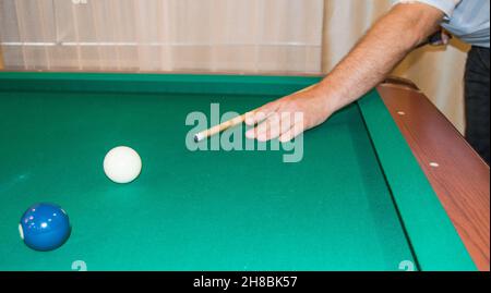 Un primo piano di un tavolo da biliardo con palle che puntano le mani dell'atleta prima di colpire. Foto Stock