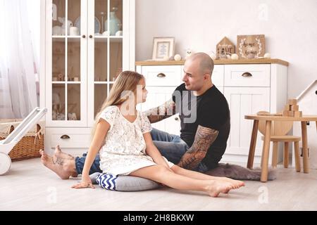 Adorabile figlia che indossa un vestito bianco con il suo padre amorevole in una moderna stanza del bambino con un arredamento di legno. Buona famiglia. Foto Stock