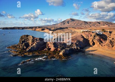 Costa de Papagayo a Lanzarote, Spagna, con i due bar e la catena montuosa Los Ajaches sullo sfondo. Una serata di sole con alcune nuvole in un b Foto Stock