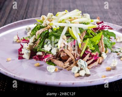 insalata con filetto di tacchino tirato, formaggio blu, lattuga fresca verde e pera dolce su un piatto, primo piano foto orizzontale Foto Stock