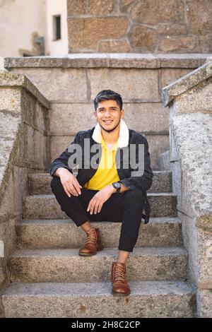 Scatto verticale del giovane uomo che guarda la fotocamera e sorride. Foto Stock