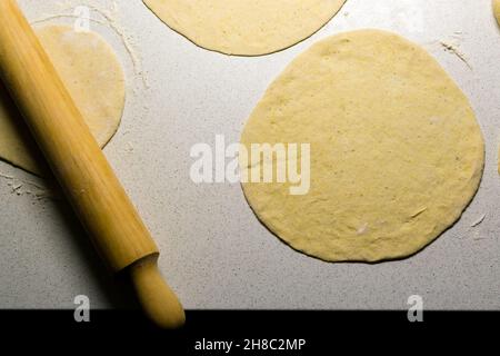 Vista dall'alto di laminello in legno e pasta per tortilla su superficie di lavoro bianca Foto Stock