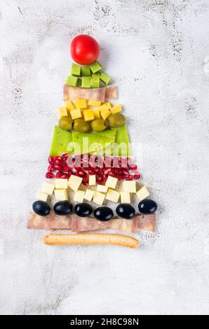 Pezzi di formaggio assortiti e frutta disposti in forma di un albero di Natale su tavola. Decorazione di festa tavola, Foto Stock