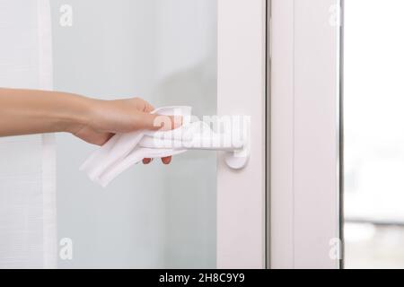 Pulizia delle maniglie delle porte con un panno antisettico e guanti. Sanitizzare la prevenzione delle superfici in ospedale e spazi pubblici contro il virus corona. Donna Foto Stock