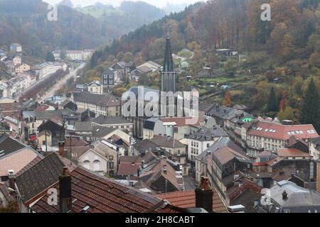 Vista della storica città termale di Plombières-les-bains, in Vosges, Francia, in una giornata di autunno nebbiosa. Vista ad alto angolo dalle colline circostanti. Foto Stock