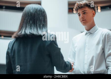 La giovane ragazza esegue una stretta di mano con il suo cliente nel suo ufficio Foto Stock