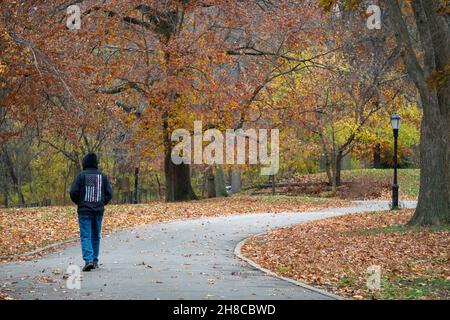 Un uomo anonimo che indossa una felpa con cappuccio e una bandiera americana rovesciata su una camminata di esercitazione in un pomeriggio coloratissimo di autunno. A Queens, New York Foto Stock