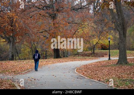 Un uomo anonimo che indossa una felpa con cappuccio e una bandiera americana su una camminata di esercitazione in un pomeriggio coloratissimo di autunno. A Queens, New York Foto Stock