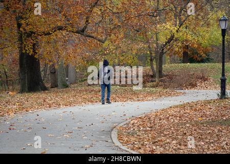 Un uomo anonimo che indossa una felpa con cappuccio e una bandiera americana su una camminata di esercitazione in un pomeriggio coloratissimo di autunno. A Queens, New York Foto Stock