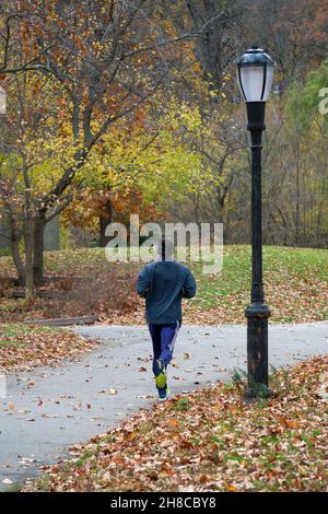 Un jogger non identificato che corre su una strada tortuosa in Kissena Park in vampate, regine, New York City, autunno 2021. Foto Stock
