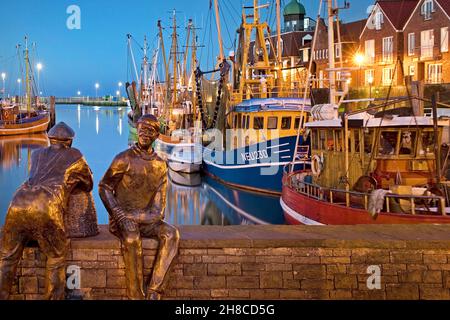 Porto di pesca con gamberetti e sculture skulptur Alt- und Jungfischer in serata, Germania, bassa Sassonia, Neuharlingersiel Foto Stock