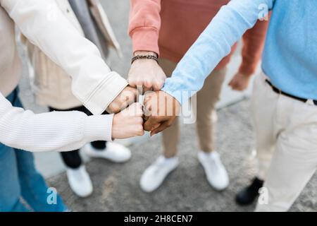 Primo piano le mani di quattro persone multirazziali che colpiscono i loro pugni in città strada Foto Stock