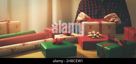 donna che avvolge regali a casa. legare un arco Foto Stock