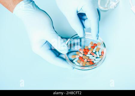 Sfondo medico astratto. Le mani del medico in guanti medici contengono pillole multicolore. Foto Stock