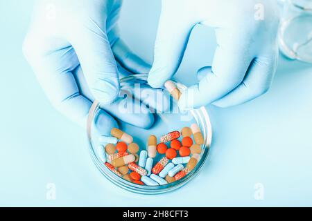 Sfondo medico astratto. Le mani del medico in guanti medici contengono pillole multicolore. Foto Stock