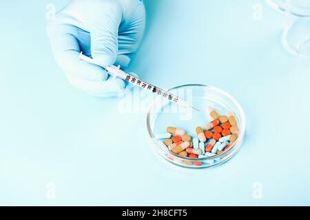 Sfondo medico astratto. Le mani del medico in guanti medici contengono pillole multicolore. Foto Stock