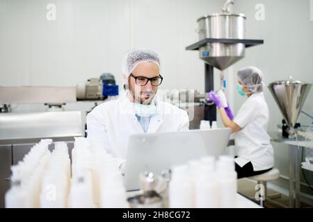 Tecnico e operatore di macchine che lavora in fabbrica di prodotti cosmetici. Foto Stock