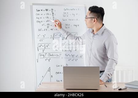 Tutor di matematica che conduce lezioni online per gli studenti di fronte a un laptop aperto Foto Stock