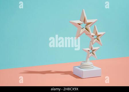 Trofeo dei vincitori con tre stelle fluttuanti su uno sfondo diagonale bicolore di arancione e verde con spazio ombra e copia Foto Stock