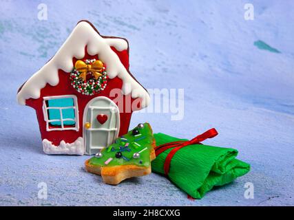 Scena di Capodanno, biscotti a forma di casa e albero di Natale e un regalo avvolto su sfondo chiaro, come la neve. Foto Stock