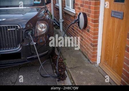 Thaxted Essex UK Electric London Taxi carica novembre 2021 Electric London Taxi carica in su al punto di chraging elettrico fissato al muro di privato h Foto Stock