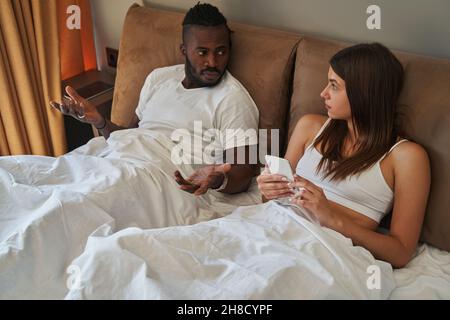 Giovane coppia mista che ha conversato in camera da letto Foto Stock