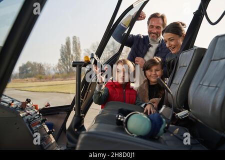 Famiglia entusiasta che si aggrappa insieme vicino all'elicottero Foto Stock